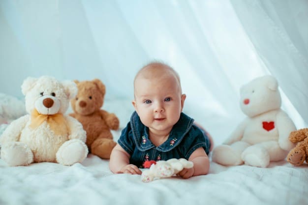 little-child-lies-among-toy-bears-on-bed_1304-3948