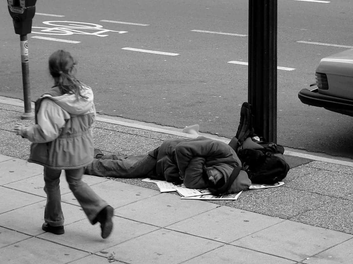 Járókelő elsétál alvó hajléktalan mellett